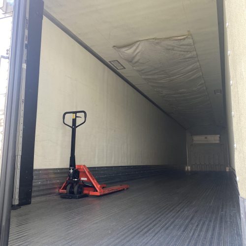 Forklift inside truck with large door.